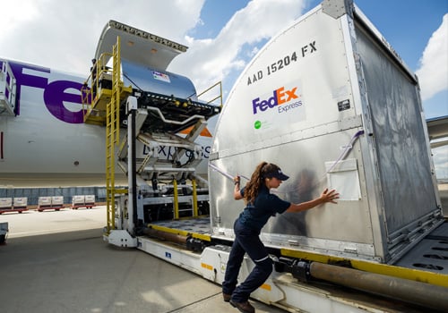 Large FedEx cargo being loaded on plane by employee